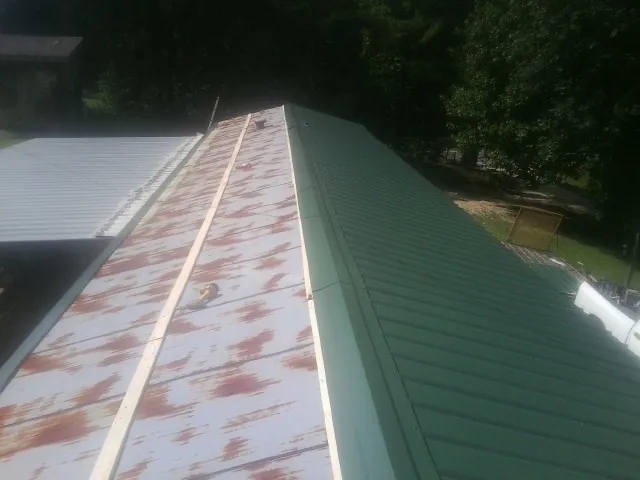 Old rusted panels beside newly installed green metal roofing — Wind Damage Roof Repair by Roofing Brothers in Raphine