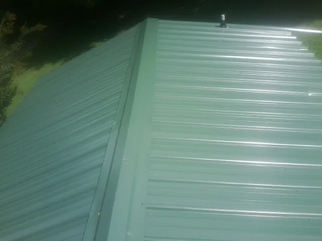 New green metal panels meeting at the ridge of a roof — Flat Roof Repair work by our crew in Raphine