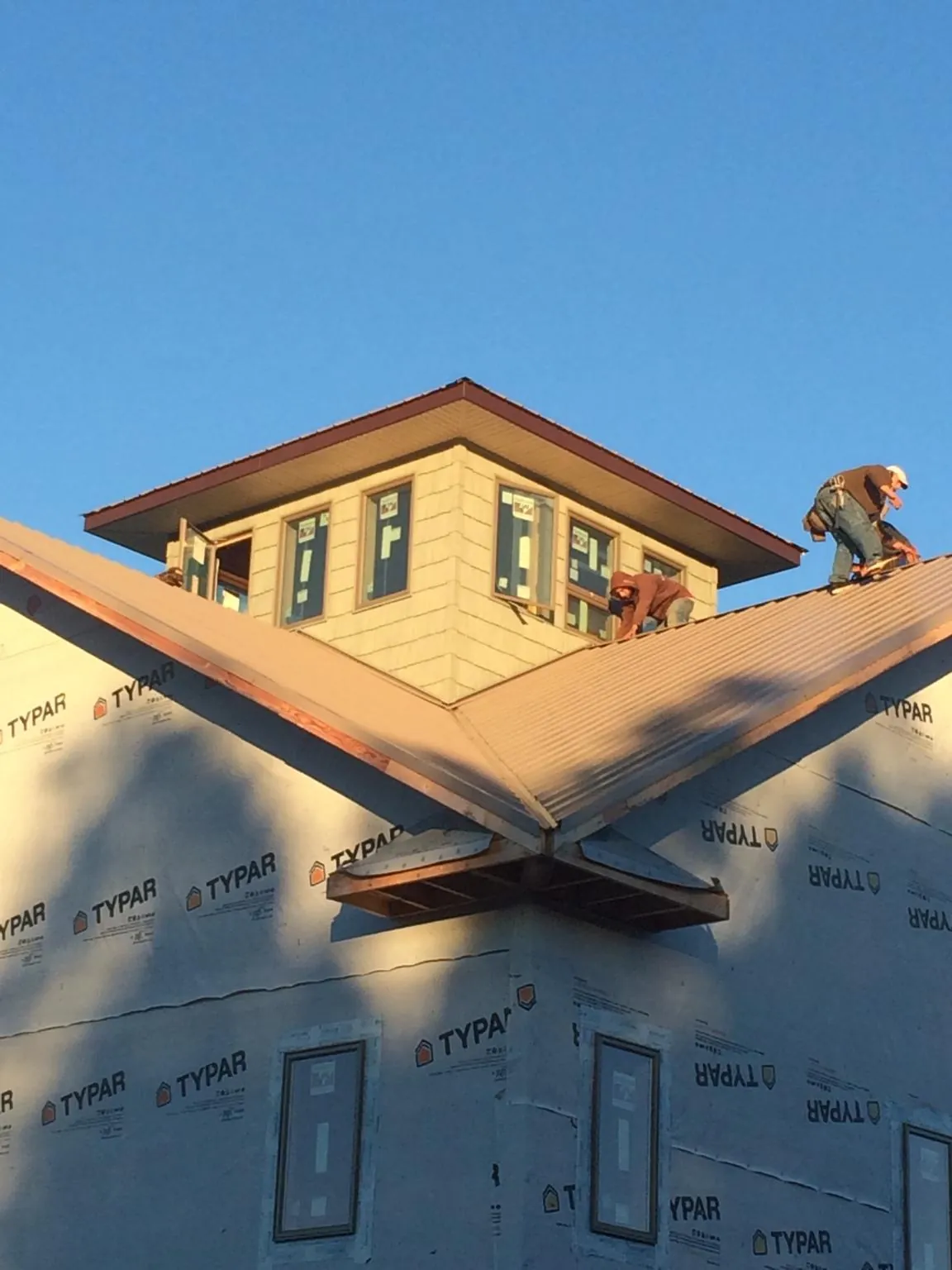 Roofers working around a rooftop cupola on a new metal roof at sunset — Roof Waterproofing in Raphine by Roofing Brothers
